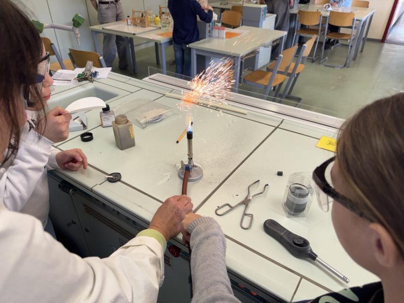 Bild zeigt ein Experiment aus dem Chemieunterricht mit Bunsenbrenner und sprühender Flamme