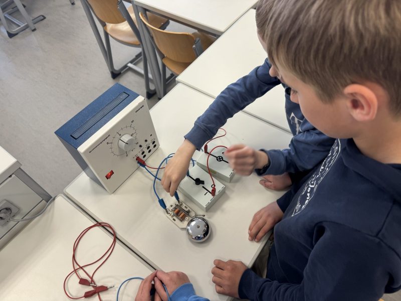 Bild zeigt Schüler schließen eine Klingel am Stromkreis an